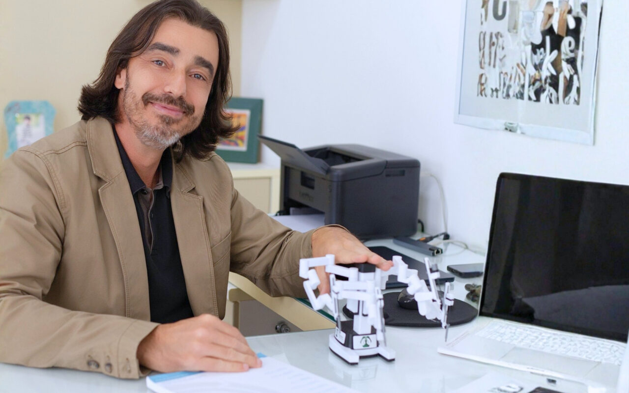Dr. Gustavo Bandeira e réplica em miniatura do sistema robótico Da Vinci, utilizado em cirurgias torácicas robóticas.